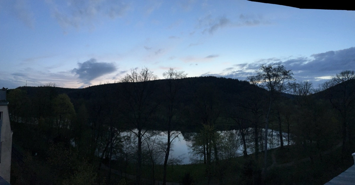 Blaue Stunde über dem Park und dem Teich an einem Frühlingsabend, gesehen vom Balkon