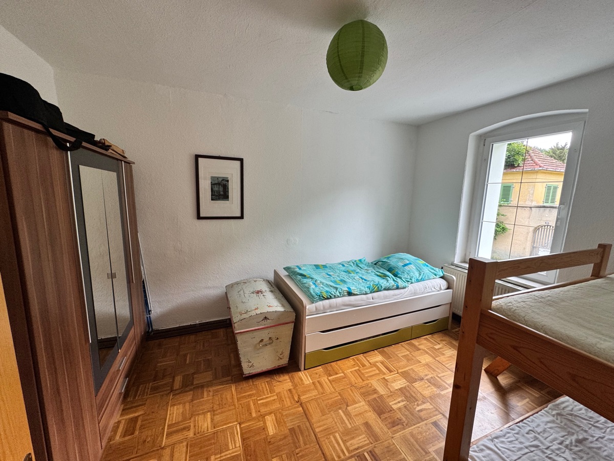Helles Schlafzimmer mit Einzelbett, Etagenbett, Parkettboden und Kleiderschrank